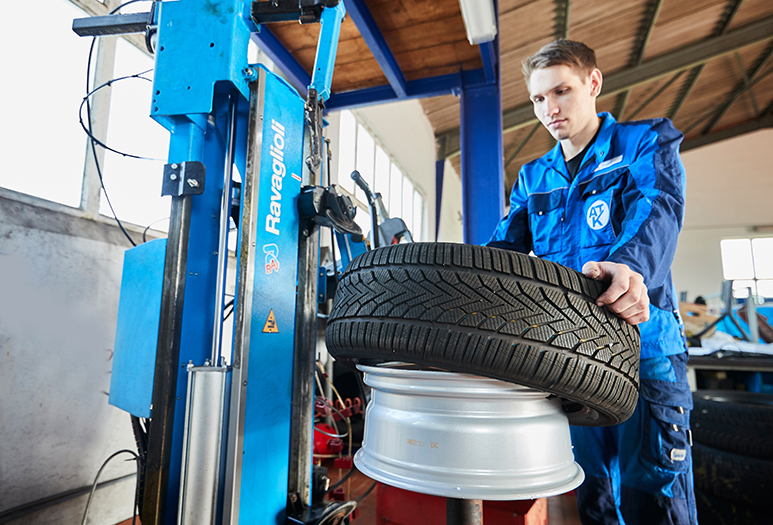 Reifenservice und Montage in der KFZ-Meisterwerkstatt Albert Tycho Kruse in Minden Mechaniker montiert einen Autoreifen auf eine Felge mit einer Reifenmontiermaschine