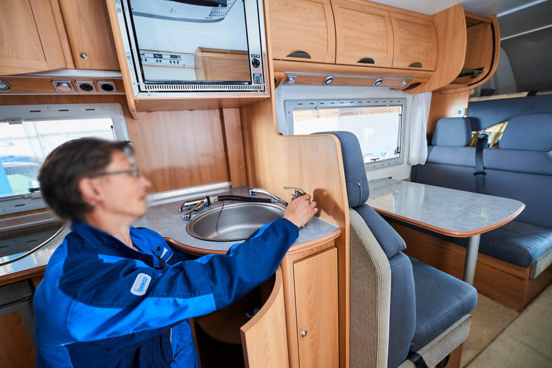 Service für Küche und Sanitär im Wohnmobil bei Albert Tycho Kruse in Minden Mechaniker arbeitet an der Kücheneinrichtung im Innenraum eines Wohnmobils