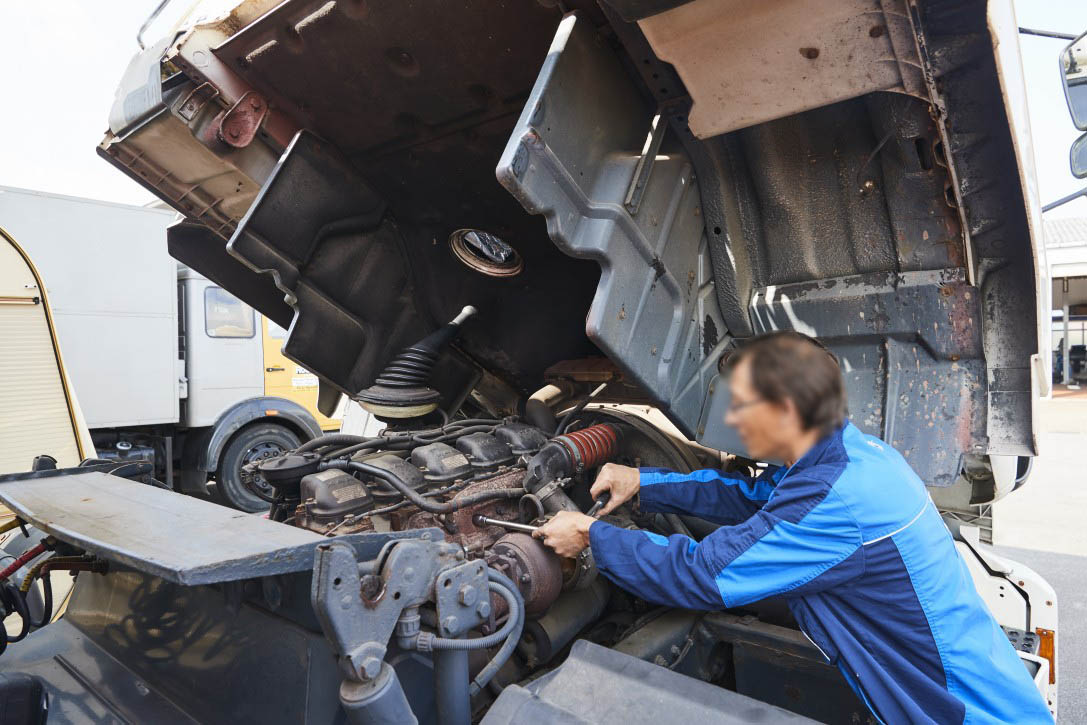 Motorservice und Reparatur für Nutzfahrzeuge bei Albert Tycho Kruse in Minden Mechaniker arbeitet am Motor eines Nutzfahrzeugs mit gekippter Fahrerkabine