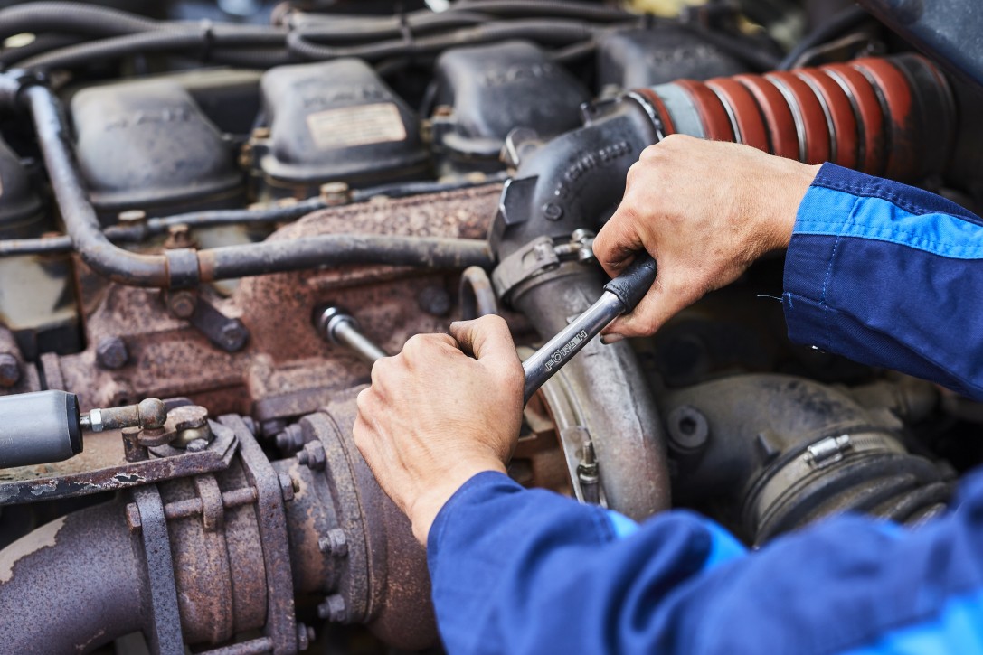 Motorservice und Instandsetzung für Nutzfahrzeuge bei Albert Tycho Kruse in Minden Hände eines Mechanikers arbeiten mit einem Schraubenschlüssel am Motor eines Nutzfahrzeugs